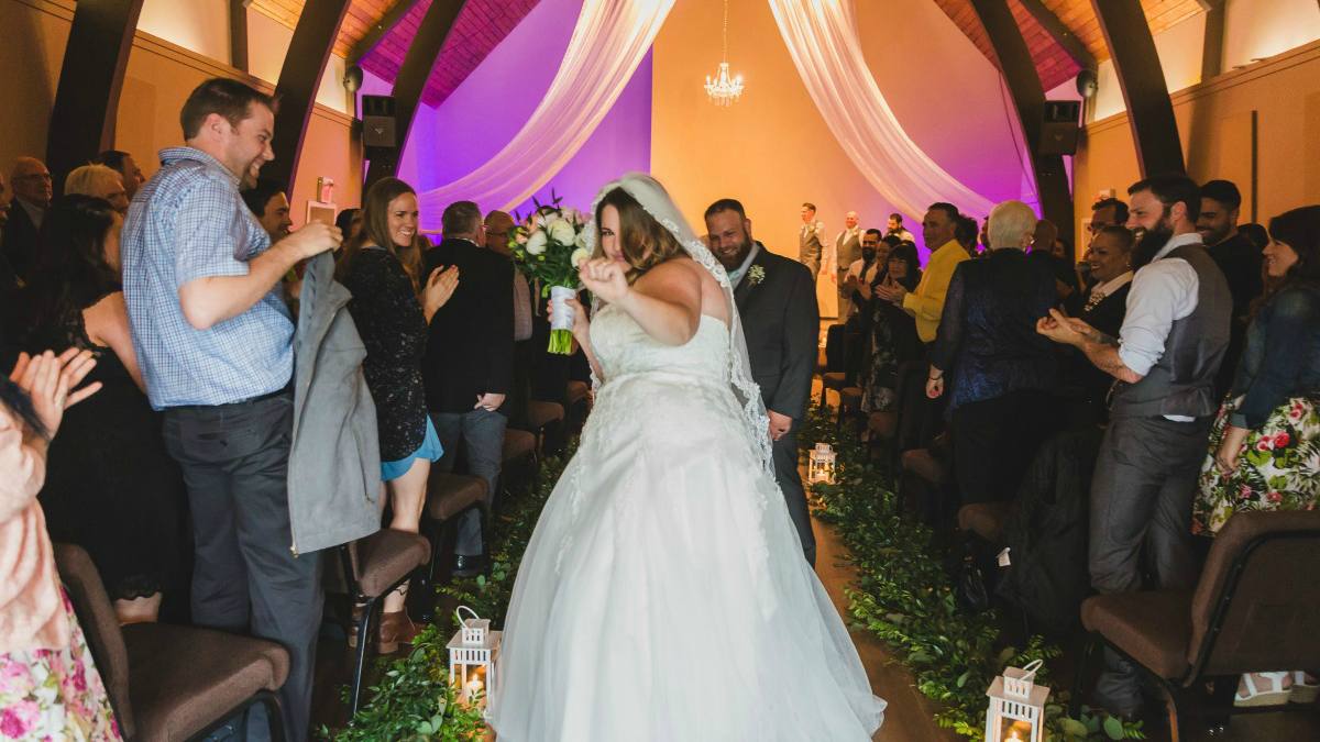 A bride walking up the aisle under draped fabric